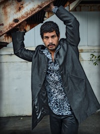 a man in a leather coat leaning against a metal railing