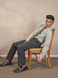 a man sitting on a chair wearing a shirt and tie